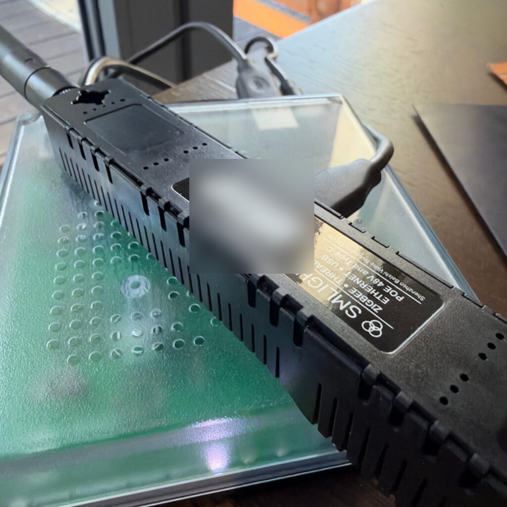 Czarna antena Zigbee i Thread SMLIGHT leżąca na obudowie centralki